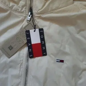 Tommy Jeans jachetă geacă bărbați crem alb-unt