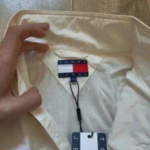 Tommy Jeans jachetă geacă bărbați crem alb-unt