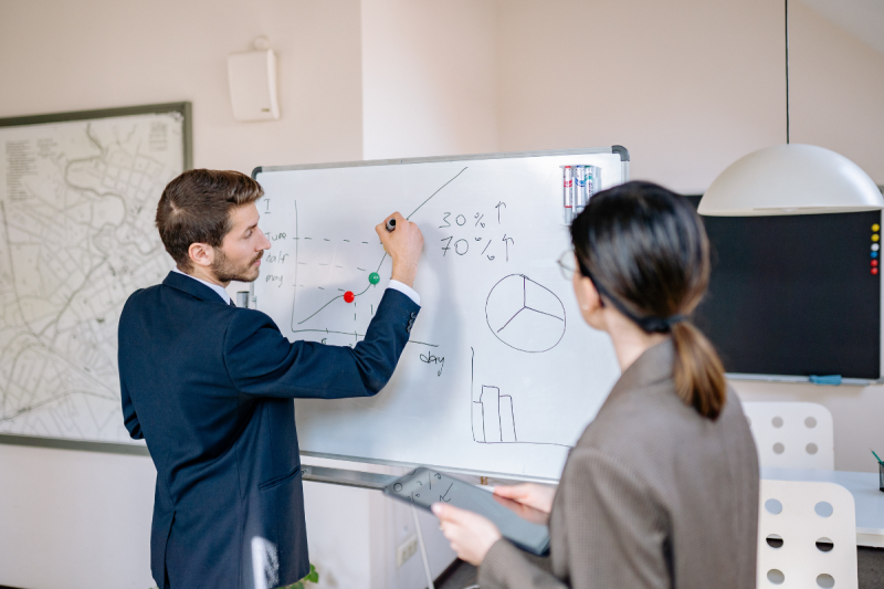 manager desenand cu marker pe whiteboard in birou manager desenand cu marker pe whiteboard in birou
