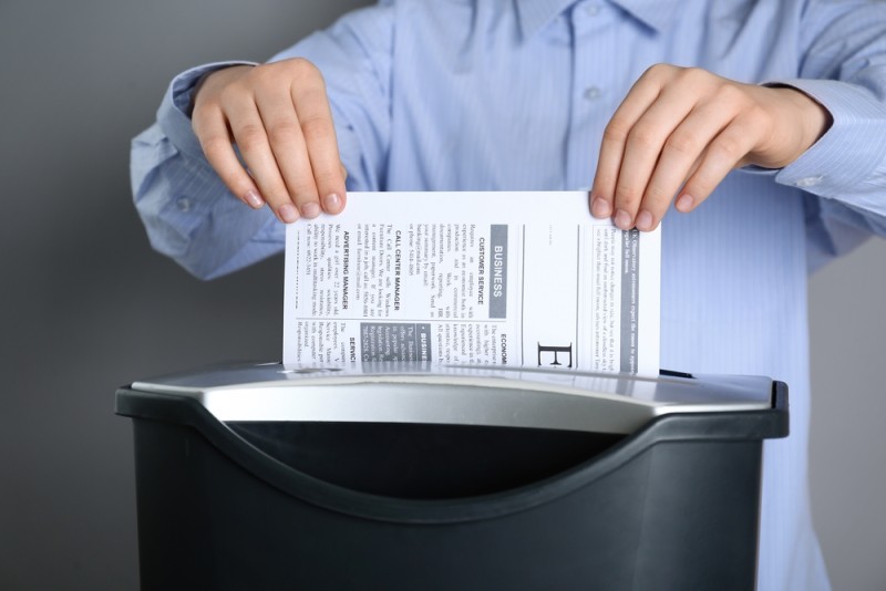  barbat care introduce un document in distrugatorul pentru documente