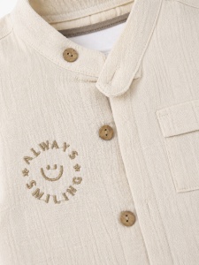 Compleu bebe baieti 3 piese din muselina cu tricou alb din bumbac si pantaloni crem, prezentare in decor