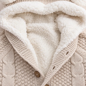 Salopeta bebe pentru iarna bej tricotata cu interior imblanit, gluga cu urechiuse si model torsadat, prezentare in decor
