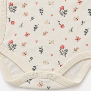 Body bebe alb crem cu maneca lunga si imprimeu floral, prezentare in decor