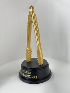 Clește auriu trofeu vedere laterală pe piedestal negru