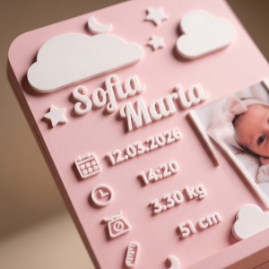 Detaliu texturat al placutei roz - nume, norisori, stelute si luna in relief, langa rama cu poza