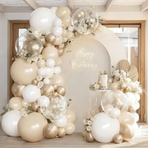 Prezentare eleganta pentru un set arcada baloane aniversare Boho Cream & Gold, montat asimetric cu baloane ivory, albe, champagne gold si transparente Bobo.