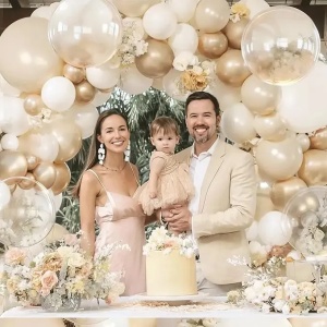 Prezentare eleganta pentru un set arcada baloane aniversare Boho Cream & Gold, montat asimetric cu baloane ivory, albe, champagne gold si transparente Bobo.