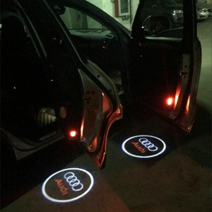 Proiecție Audi pe sol la deschiderea portierelor, surprinsă pe timp de noapte, pentru evidențierea efectului luminos în utilizare reală.